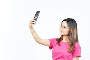 Machen Sie ein Selfie mit dem Smartphone einer schönen Asiatin, die auf weißem Hintergrund isoliert ist foto