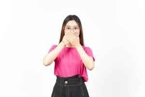 Mund mit Schockgesichtsausdruck der schönen asiatischen Frau bedeckend, die auf weißem Hintergrund lokalisiert wird foto