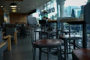Nahaufnahme moderner Holzstuhl auf der Metallstruktur im Café mit verschwommenem Innencafé im Hintergrund foto