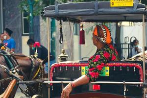 yogyakarta, indonesien im oktober 2022. rückansicht eines wagen- oder andong-fahrers auf jalan malioboro, yogyakarta. foto