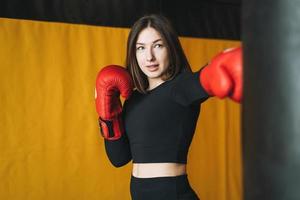 junge brünette frau in schwarzer kleidung verlobt sich mit dem boxtraining im fitnessstudio des fitnessclubs foto