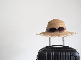 nahaufnahme retro-hut mit sonnenbrille über gepäck auf weiß isoliertem raum urlaubs- und reisekonzept foto