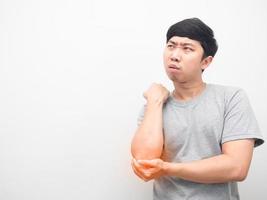 asiatischer mann schmerzt seinen ellbogen und schaut auf den kopierraum foto