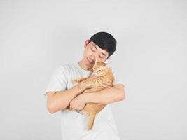 asiatischer Mann trägt und umarmt schöne Katze orange Farbe auf weißem, isoliertem Hintergrund foto