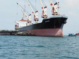industrieschiff mit großem kran logistikboot im ozean und blauem himmel, transport industrieschiffskonzept foto