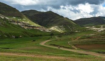 Berittener Sotho-Mann, der in die Landschaft von Lesotho reitet foto