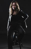schöne amerikanische Frau posiert auf schwarzem Hintergrund mit schwarzer Lederjacke. Mode-Modell trägt Lederhose und Jacke Mode-Modell trägt Lederjacke foto