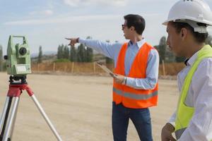 Vermessungsingenieur misst das Niveau auf der Baustelle. Vermessungsingenieure sorgen für genaue Messungen, bevor sie große Bauprojekte in Angriff nehmen. foto