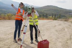 Vermessungsingenieur misst das Niveau auf der Baustelle. Vermessungsingenieure sorgen für genaue Messungen, bevor sie große Bauprojekte in Angriff nehmen. foto