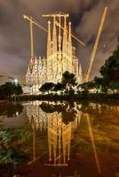 la sagrada familia nachts beleuchtet, im wasser widerspiegelnd. die kathedrale wurde von antoni gaudi entworfen und befindet sich seit 1882 im bau in barcelona, spanien, 2022 foto