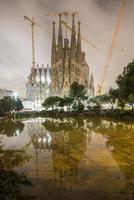 la sagrada familia nachts beleuchtet, im wasser widerspiegelnd. die kathedrale wurde von antoni gaudi entworfen und befindet sich seit 1882 im bau in barcelona, spanien, 2022 foto