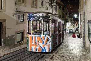 vintage berühmte bica straßenbahn nachts mit graffiti in lissabon, portugal. foto