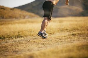 Läufer eines jungen Mannes, der auf einer Bergstraße läuft. Jogger-Trainingstraining im Fitnessschuh. gesundes lebensstil- und sportkonzept. Bewegungsunschärfe und selektiver Fokus. foto