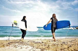 Surferpaar wartet auf die hohen Wellen am Strand - sportliche Menschen mit Surfbrettern am Strand - Extremsport- und Urlaubskonzept foto