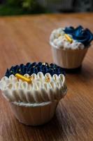 luxuriöse und elegante Cupcakes mit weißer Creme und Marineblau mit goldenen Streuseln. foto