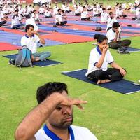 neu-delhi, indien, 21. juni 2022 - gruppen-yoga-übungssitzung für menschen im yamuna-sportkomplex in delhi am internationalen yoga-tag, große gruppe von erwachsenen, die an yoga-kursen im cricket-stadion teilnehmen foto