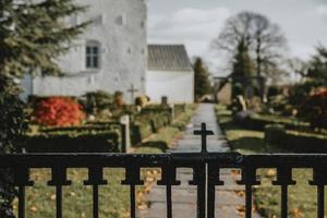 das detail des christlichen kreuzes auf dem oberen teil des eingangstors zum jelling friedhof in dänemark mit den ältesten wikinger-runensteinen während des herbsttages foto