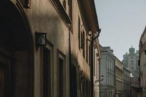 das spiel des nachmittagssonnenlichts an den wänden alter gebäude im historischen zentrum der polnischen stadt krakau mit erleuchteter straßenlaterne im hintergrund foto