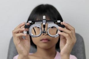 mädchen, das versuchsrahmenbrillen hält, testaugenkonzept foto
