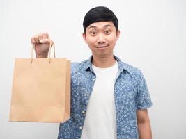 blaues Hemd des asiatischen Mannes, das Einkaufstaschenporträt hält foto