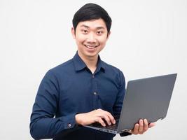 glückliches Lächeln des asiatischen Mannes, das weißen Hintergrund des Laptops hält foto