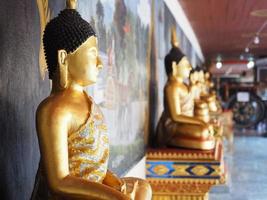 Nahaufnahme der goldenen Farbe der Buddha-Statue vor vielen Buddha-Statuen verschwimmen im Hintergrund im Tempel von Thailand, Chiang Mai, Dezember 2018. foto