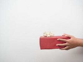 Frauenhand, die roten Geschenkkasten auf weißem Hintergrundkopienraum gibt foto