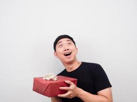 asiatischer mann, der geschenkbox hält, lächelnd und auf kopienraum schaut