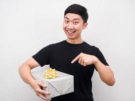 glücklicher Mann zeigt mit dem Finger auf die Geschenkbox in seiner Hand foto