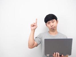 Mann hält Laptop-Geste gelangweilt und zeigt mit dem Finger nach oben auf den Kopierbereich foto