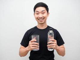 Cheefull Mann asiatischen Holding Wasserflasche und Glas in der Hand weißen Hintergrund foto