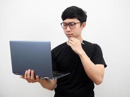 asiatischer mann trägt eine brille mit einem laptop, der denkt und sich verwirrt fühlt, ernstes gesicht auf weißem hintergrund foto