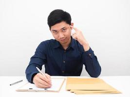asiatischer mann, der dokument auf tisch schreibt und finger auf seinen kopf zeigt, um konzept zu denken foto