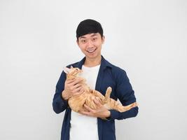 asiatischer mann, der nette katze in seiner hand mit glücklichem lächeln auf weißem lokalisiertem hintergrund hält foto