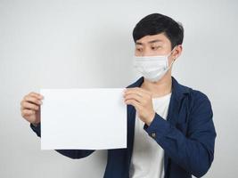 asiatischer mann mit maske schützt den blick auf leeres papier in seiner hand auf weißem hintergrund foto