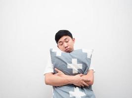 asiatischer Mann schläfriges Gesicht Umarmungskissen auf weißem Hintergrund faules Konzept foto