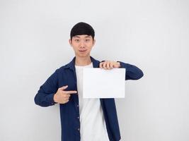 asiatischer mann zeigt mit dem finger auf leeres papier in seiner hand und schaut in die kamera auf weißem isoliertem hintergrund foto