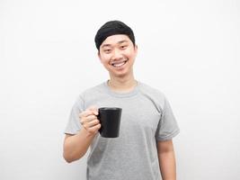 asiatischer mann, der kaffeetasse hält, die glücklichen gefühlsweißen hintergrund lächelt foto