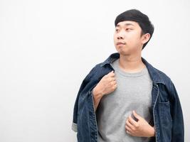 asiatischer mann, der jeanshemd hält, bedecken seinen körper selbstbewusst und betrachten den kopienraum foto