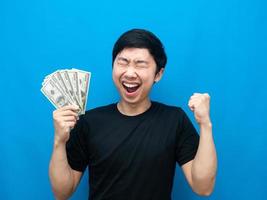 Mann, der sich glücklich fühlt, Geld zu halten, zeigt Faust auf blauem Hintergrund foto