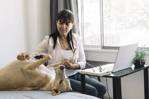 Junge Geschäftsfrau, die ihren Hund streichelt, während sie zu Hause arbeitet. foto