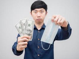 Nahaufnahmegelddollar und -maske in der Hand des Mannes auf weißem Hintergrund foto
