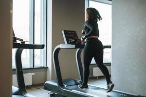 Junge Fitness Brünette Frau Training für Cardio-Laufband im Fitnessstudio foto