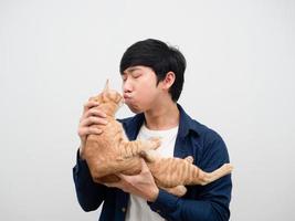 porträt asiatischer mann, der katze hält und gesichtsweißhintergrund küsst foto