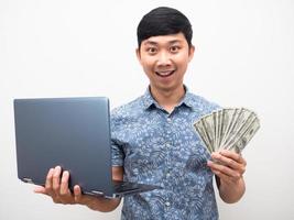 blaues hemd des mannes, das laptop mit viel geld hält, aufgeregtes gesicht isoliert foto