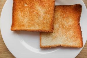 frisch gebackenes Toasterbrot. leckeres geröstetes Brot auf Holzbrett. ein paar knusprige Toasts im Toaster, Nahaufnahme. leckeres Frühstück foto