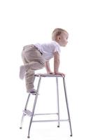 kleiner Junge klettert auf einen Leiterstuhl. der Beginn eines Karrierekonzepts. lustiger kleiner Junge isoliert auf weißem Hintergrund. foto