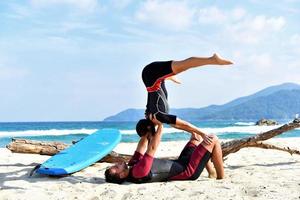 fittes sportliches paar, das zusammen mit dem partner acro yoga praktiziert. Fittes sportliches Paar, das gemeinsam akrobatisches Yoga am Strand praktiziert foto