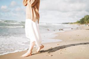 Erntefoto einer jungen schönen Frau in beigem Pullover, die das Leben am Meeresstrand bei Sonnenuntergang genießt foto