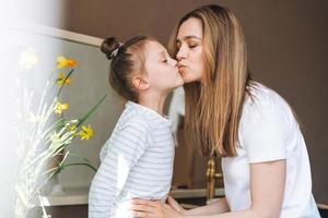 junge mutterfrau mit langen haaren mit kleiner tween-mädchentochter im pyjama, die morgens zu hause spaß hat foto